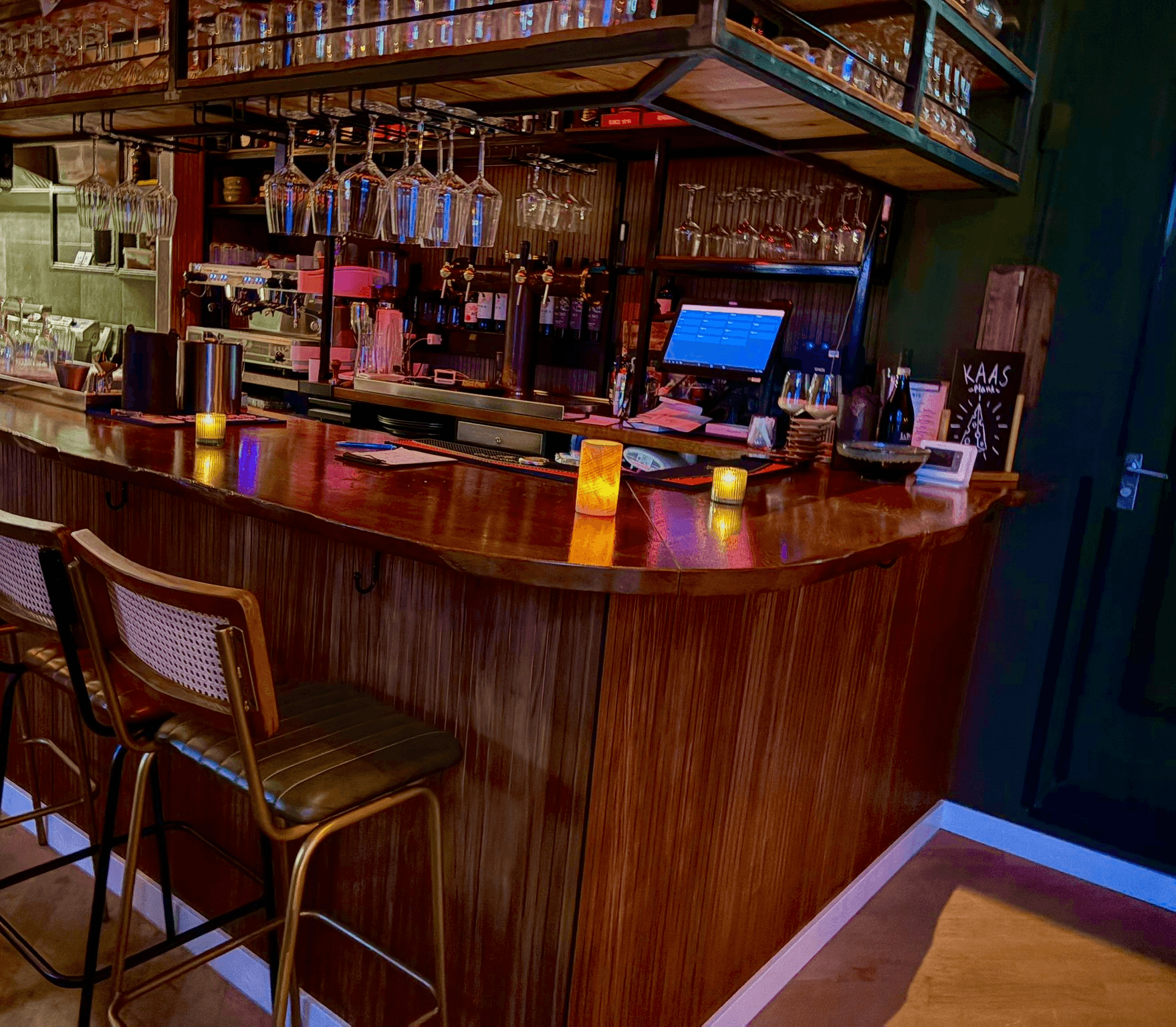 Houten bar van R.I.O. met barkrukken, glazen en sfeerverlichting