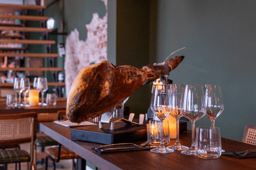 Spaanse jamón op een standaard tussen gedekte tafels bij R.I.O.